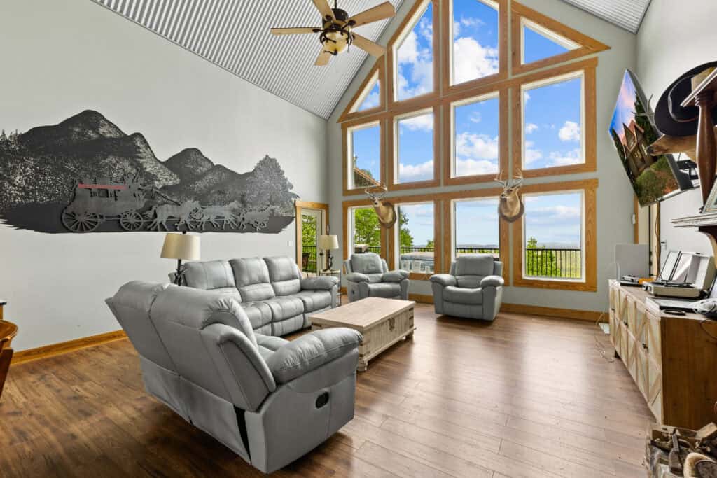 Bright living room with vaulted ceiling, mountain mural, large windows, and a comfortable seating area