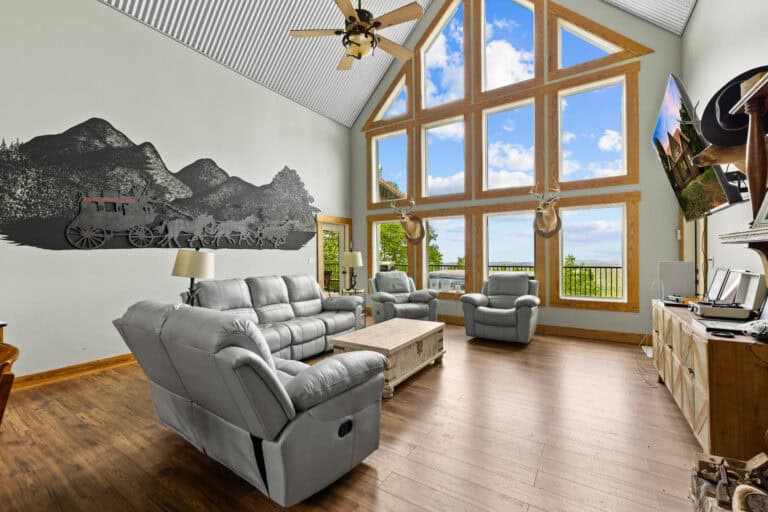 Bright living room with vaulted ceiling, mountain mural, large windows, and a comfortable seating area