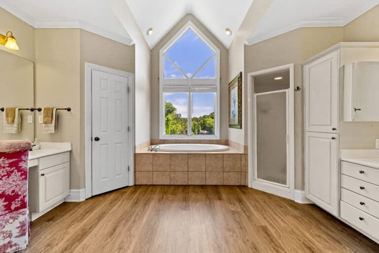 Bright residential bathroom with a freestanding tub, walk-in shower, and vaulted ceiling photographed for real estate marketi